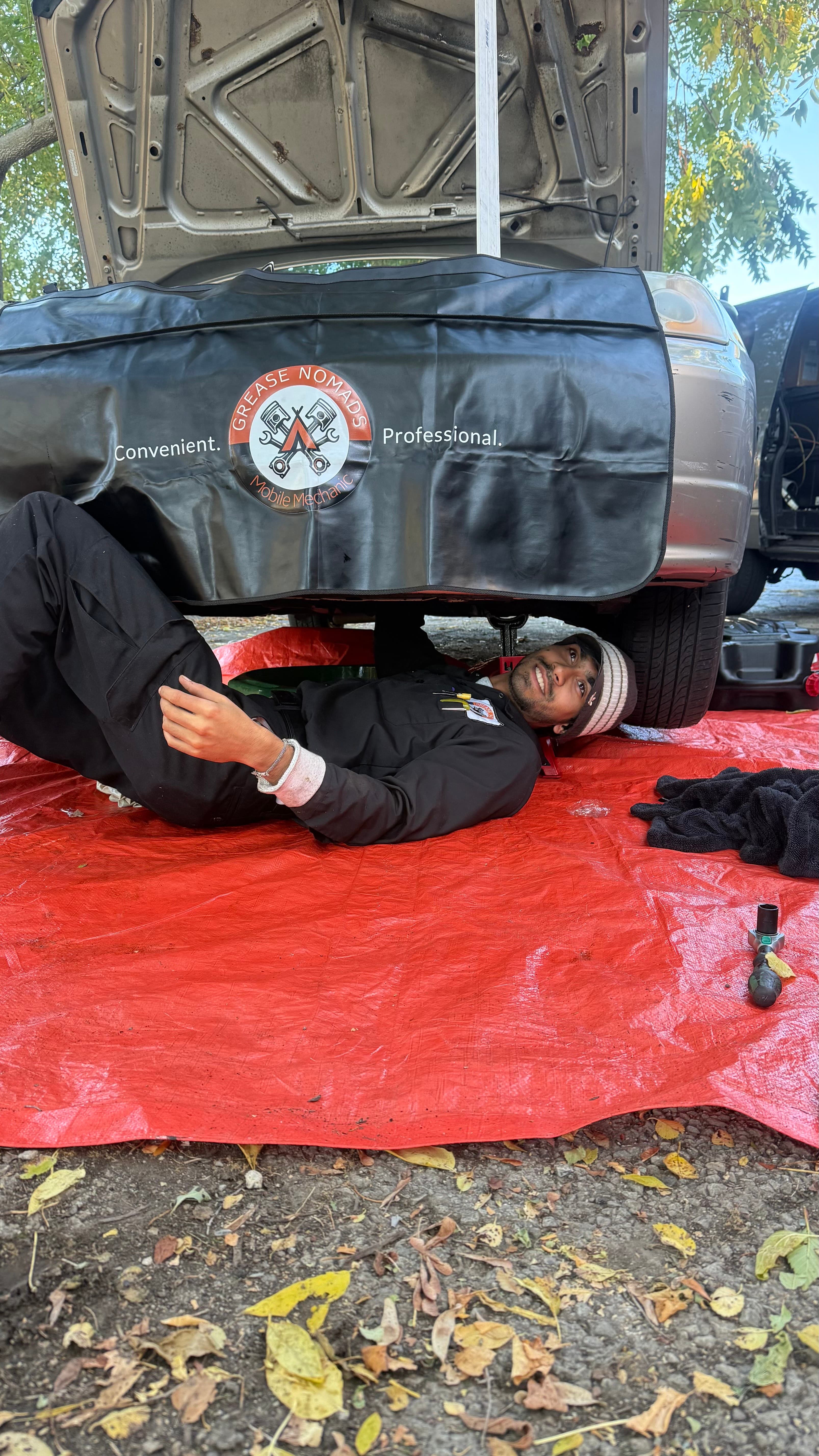 Professional mobile mechanic working under a car on site